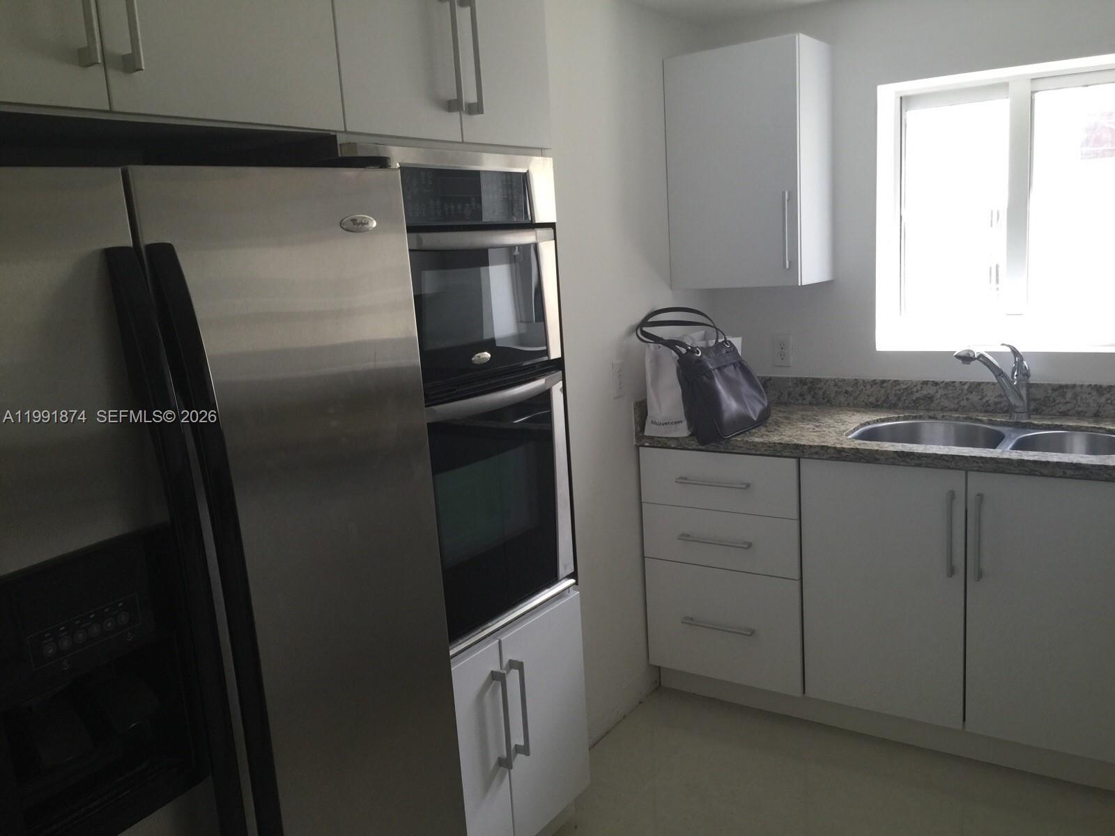A kitchen features stainless steel appliances, white cabinets, and granite countertops near a window — 170 SE 14th St # 3005, Miami FL 33131, MIAMI, FL