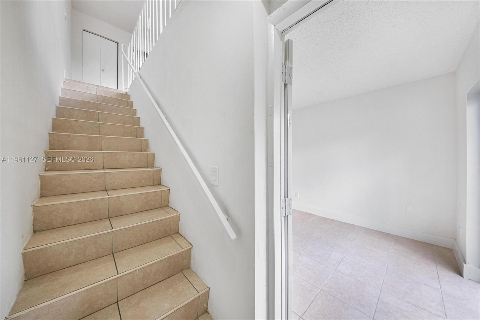 A staircase with tan tiled steps leads upward next to a doorway into a room — 1283 W 42nd St # 2, Hialeah FL 33012, HIALEAH, FL