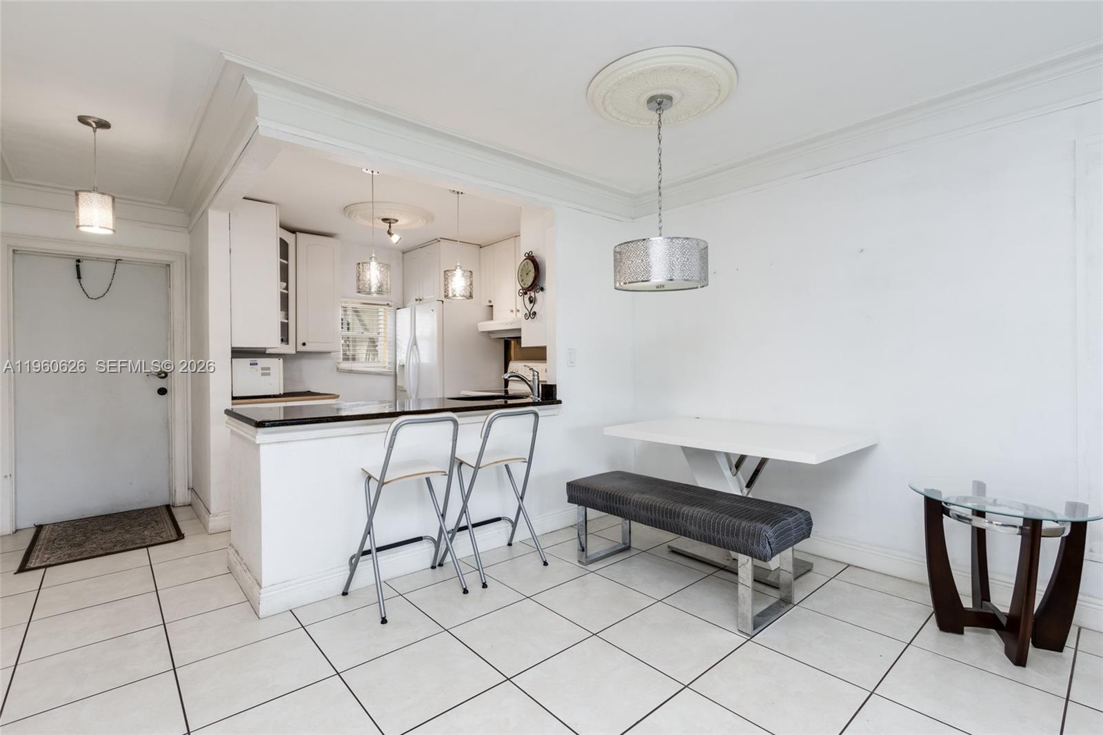 A kitchen with a breakfast bar and dining area features white cabinets and tile flooring — 4341 NW 16th St # 101, Lauderhill FL 33313, LAUDERHILL, FL