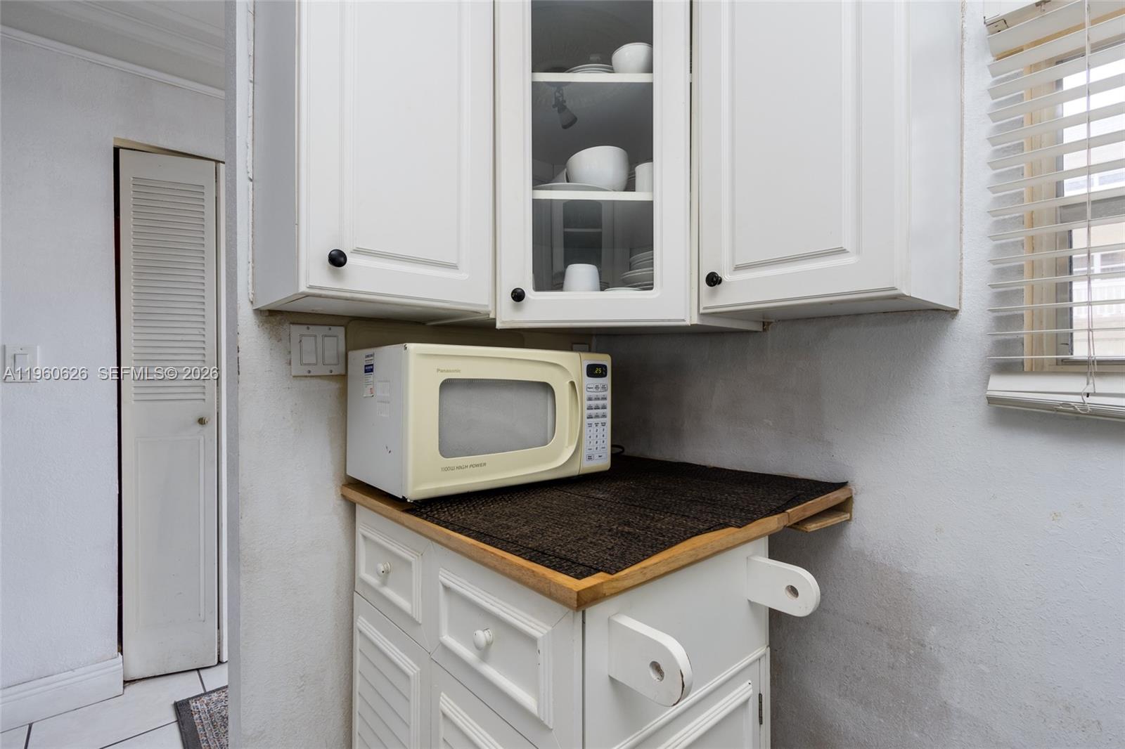 A kitchen corner features white cabinets, a microwave on a wooden cart, and a window — 4341 NW 16th St # 101, Lauderhill FL 33313, LAUDERHILL, FL