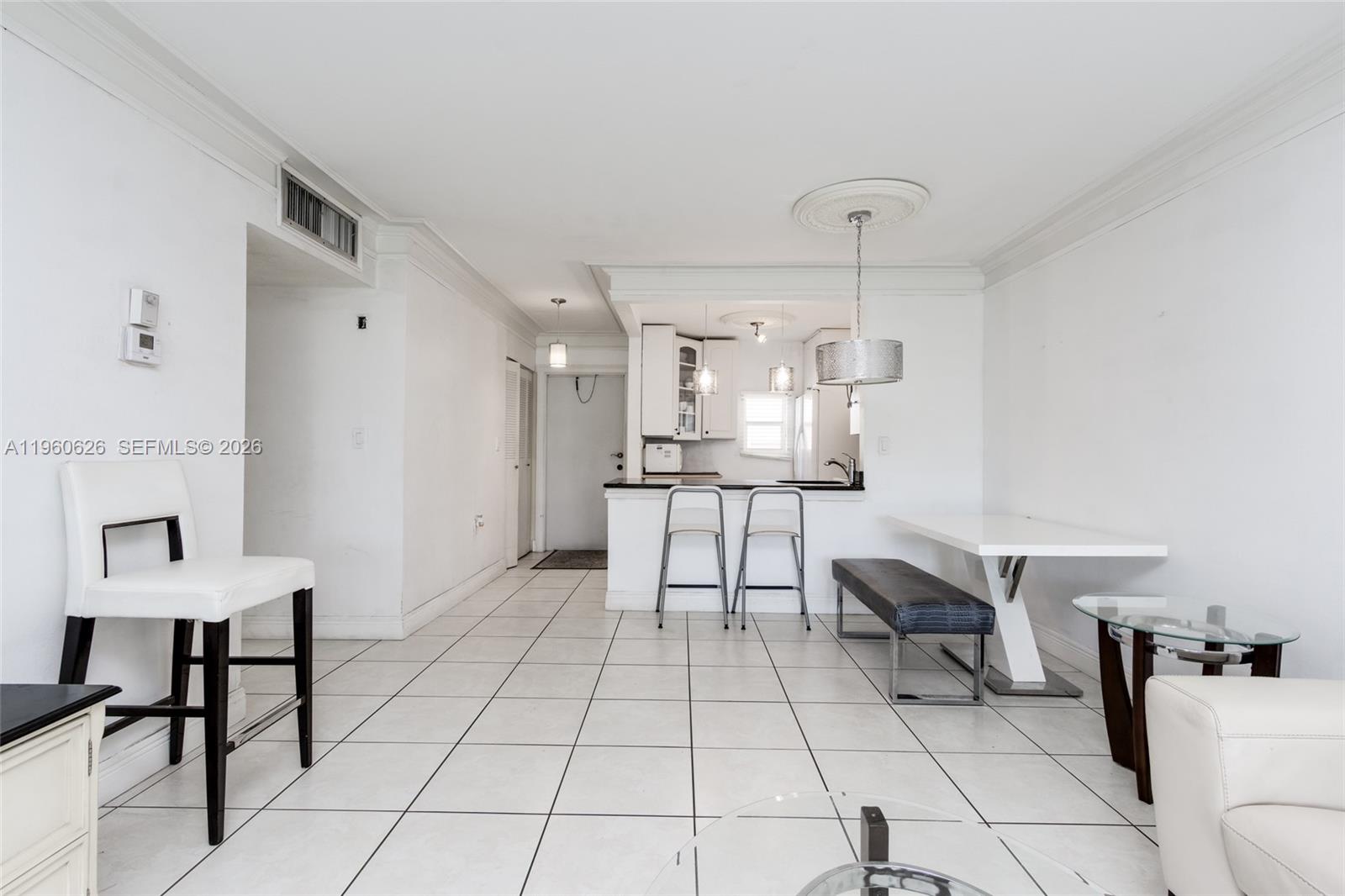 A white-tiled dining and kitchen area features a breakfast bar, pendant lighting, and modern furniture — 4341 NW 16th St # 101, Lauderhill FL 33313, LAUDERHILL, FL
