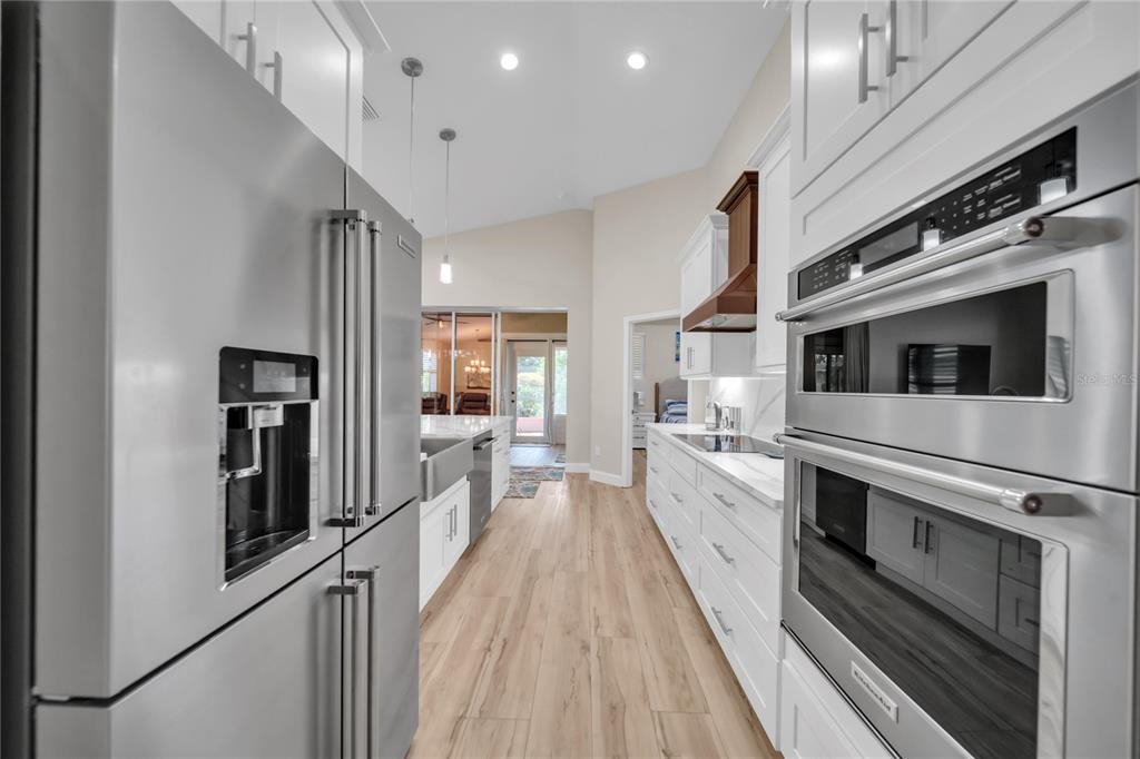 A modern kitchen features white cabinetry, stainless steel appliances, and wood-look flooring — 1358 HEDGEWOOD CIRCLE, NORTH PORT, FL