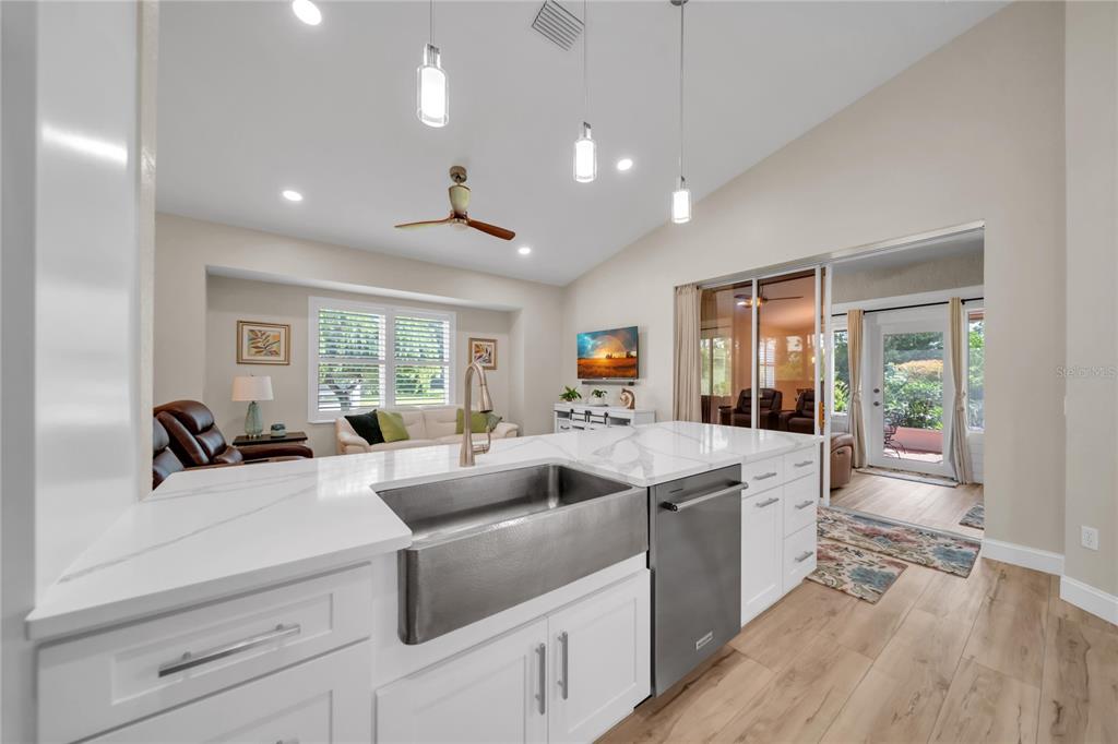 A kitchen island with a farmhouse sink and white countertops overlooks a living room area — 1358 HEDGEWOOD CIRCLE, NORTH PORT, FL