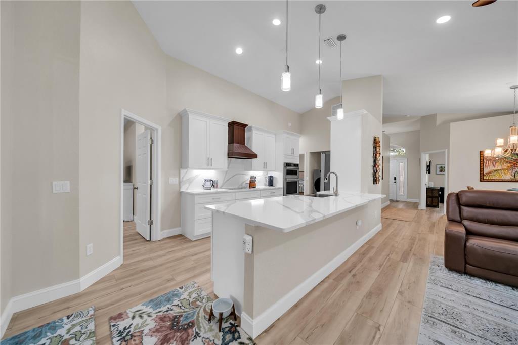 A kitchen with white cabinets, a marble-topped island, and light wood flooring — 1358 HEDGEWOOD CIRCLE, NORTH PORT, FL