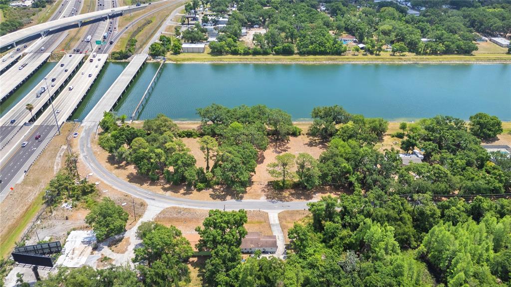 An aerial view shows a wooded lot next to a canal and a highway bridge — 5015 GARDEN LANE, TAMPA, FL
