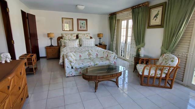 A bedroom features a floral-patterned bed and sofa, tile flooring, and green curtains — 27 SAN MIGUEL, HUMACAO, PR