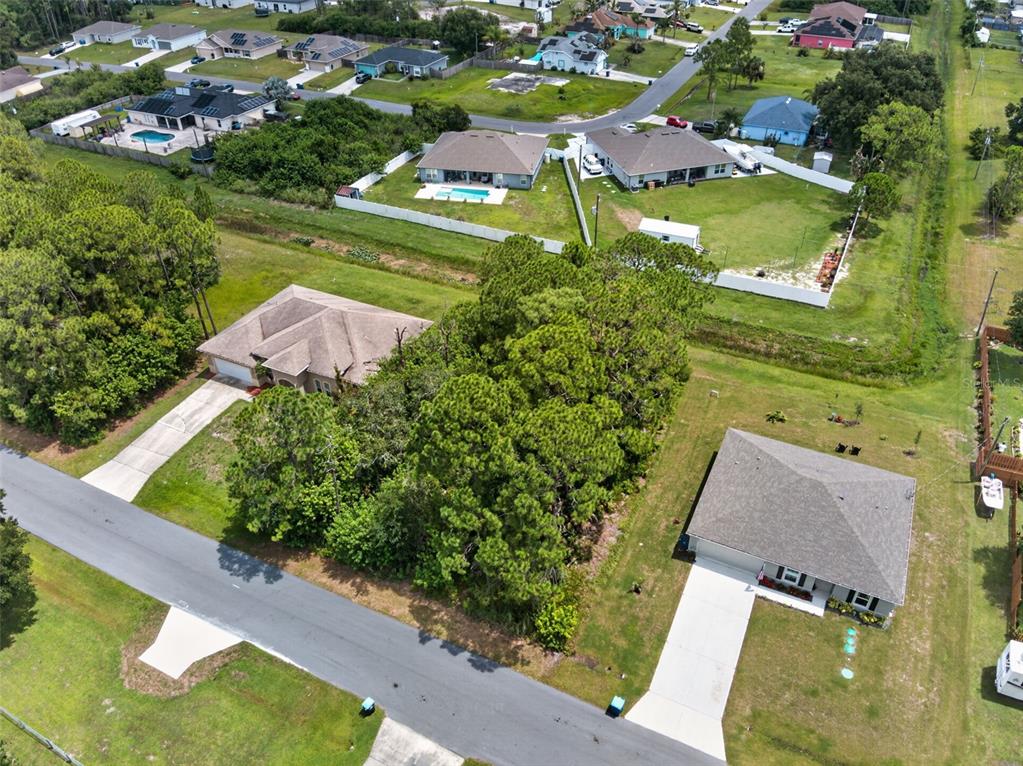 An aerial view shows two houses separated by a large, wooded vacant lot — 2669 PALOMAR AVENUE SE, PALM BAY, FL