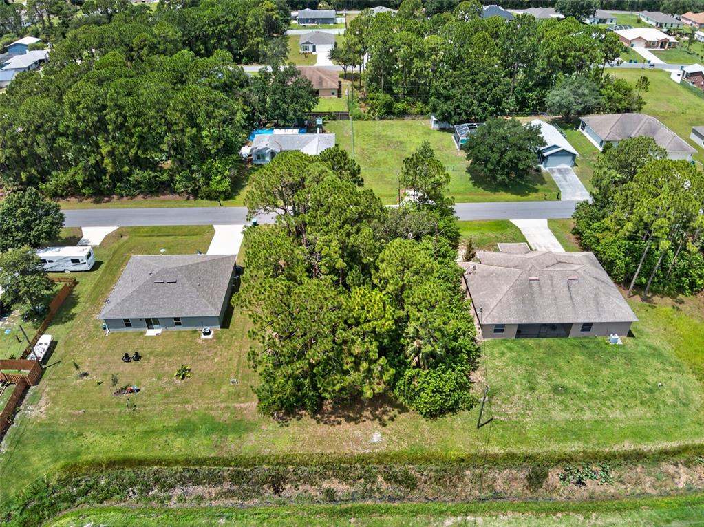 An aerial view shows two houses separated by a large, wooded lot with a canal behind — 2669 PALOMAR AVENUE SE, PALM BAY, FL