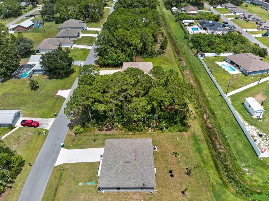 An aerial view shows a residential neighborhood with houses, driveways, and a wooded lot — 2669 PALOMAR AVENUE SE, PALM BAY, FL