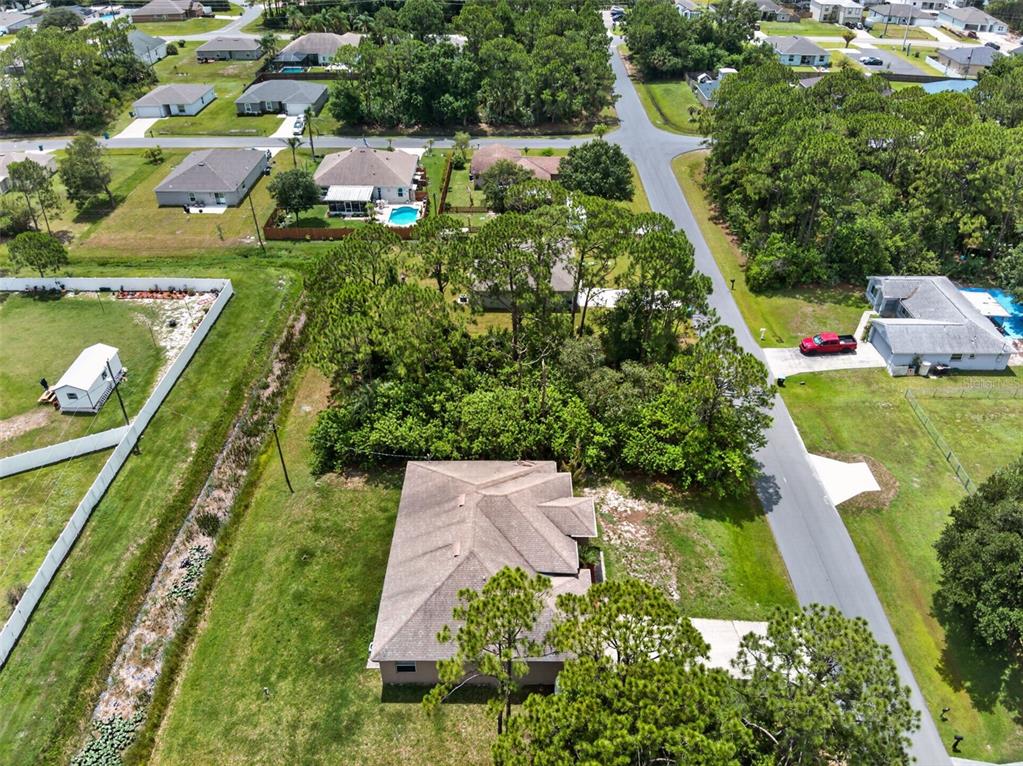An aerial view shows a residential house with a large backyard and surrounding wooded area — 2669 PALOMAR AVENUE SE, PALM BAY, FL