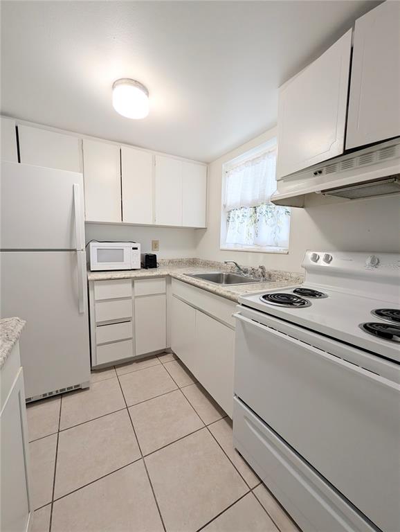 A kitchen with white cabinets, white appliances, a tiled floor, and a window above the sink — 5872 EASY STREET UNIT L2, BRADENTON, FL