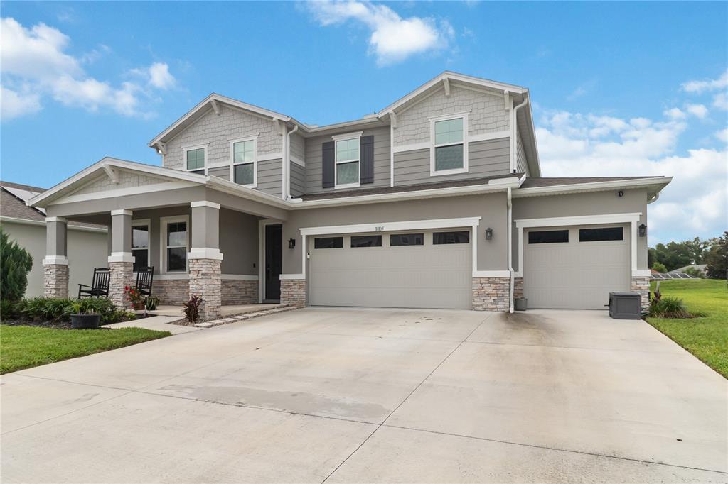 A two-story suburban house with a gray exterior, stone accents, and a three-car garage — 10105 SPRING LAKE DRIVE, CLERMONT, FL