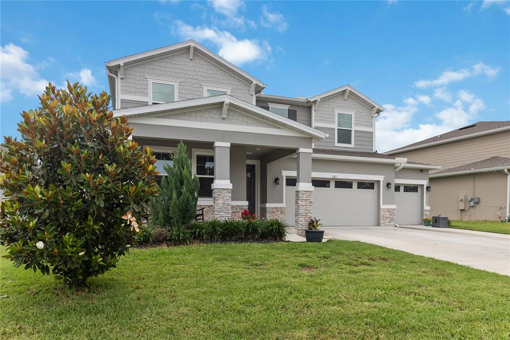 A two-story house with a gray exterior, stone accents, a covered porch, and a driveway — 10105 SPRING LAKE DRIVE, CLERMONT, FL