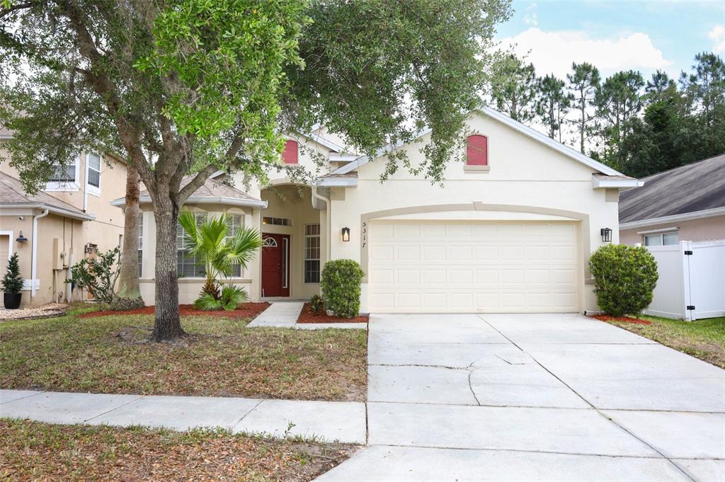 A single-story house with a beige stucco exterior, a two-car garage, and a red door — 5317 FLORENCE HARBOR DRIVE, ORLANDO, FL