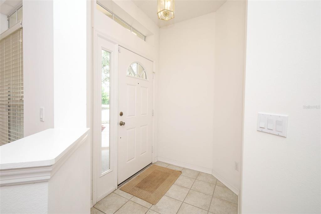A bright entryway features a white front door with a sidelight, tile flooring, and walls — 5317 FLORENCE HARBOR DRIVE, ORLANDO, FL