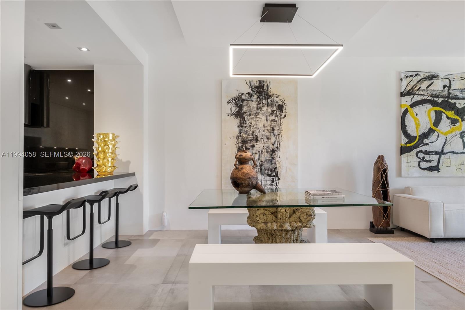 A modern dining area features a glass-top table, white benches, and a minimalist light fixture — 201 Crandon Blvd # 227, Key Biscayne FL 33149, KEY BISCAYNE, FL
