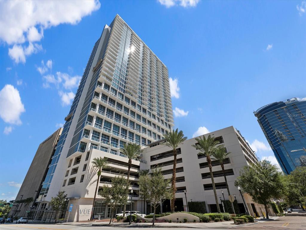 A low-angle exterior view of a tall residential high-rise building with an attached parking garage — 150 E ROBINSON STREET UNIT 3409, ORLANDO, FL