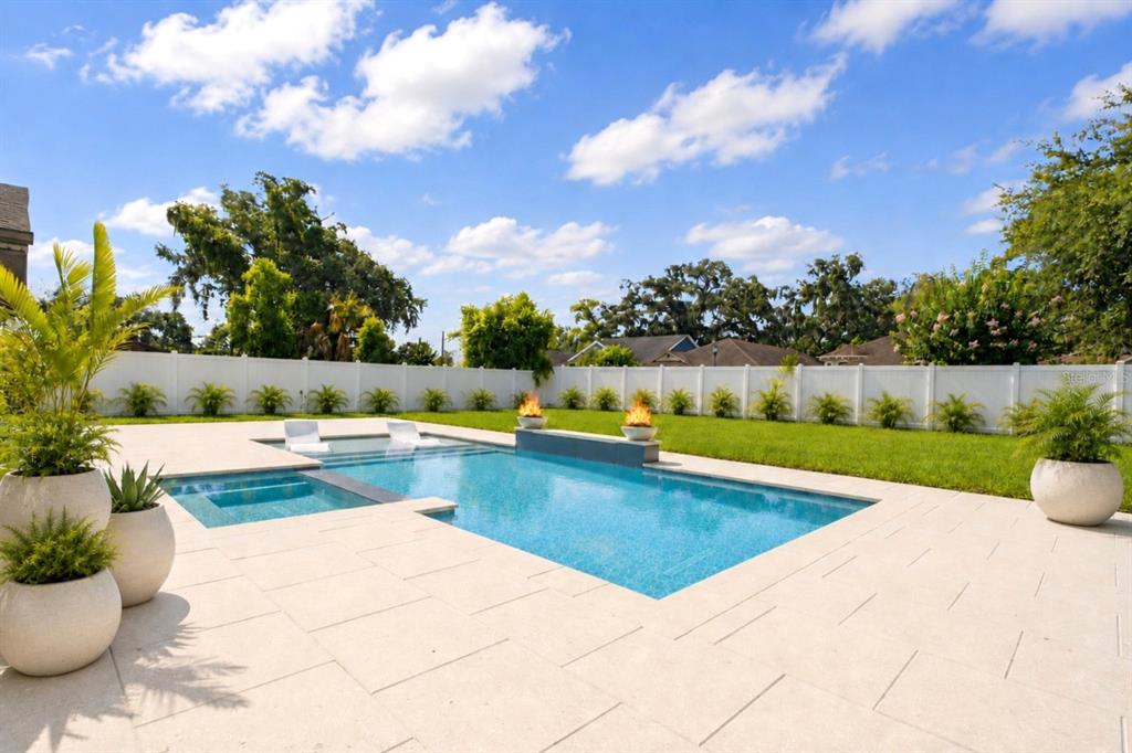 A rectangular swimming pool with a spa and fire bowls sits on a paved patio — 906 SAMY DRIVE, TAMPA, FL