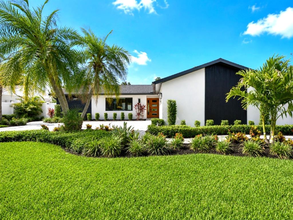 A modern single-story house with white and black exterior walls, palm trees, and manicured landscaping — 906 SAMY DRIVE, TAMPA, FL