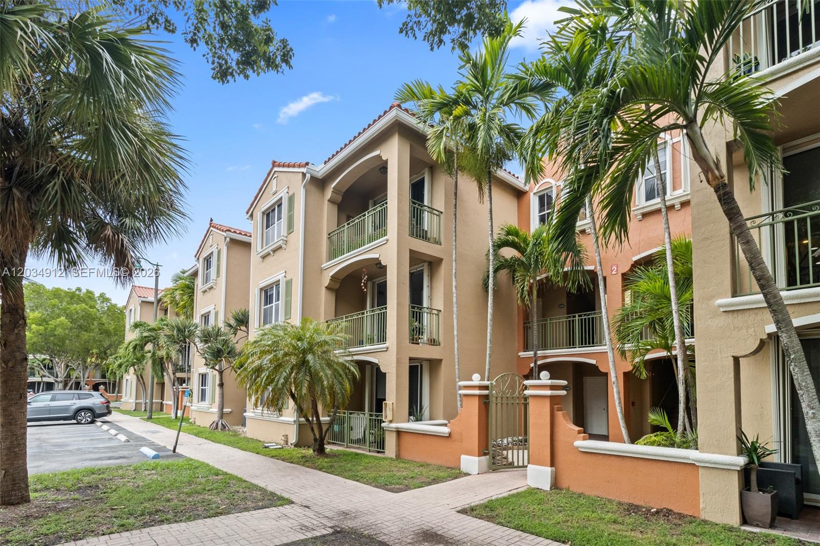 Exterior view of a multi-story apartment building with balconies, palm trees, and a parking lot — 6540 NW 114th Ave # 1423, Doral FL 33178, DORAL, FL