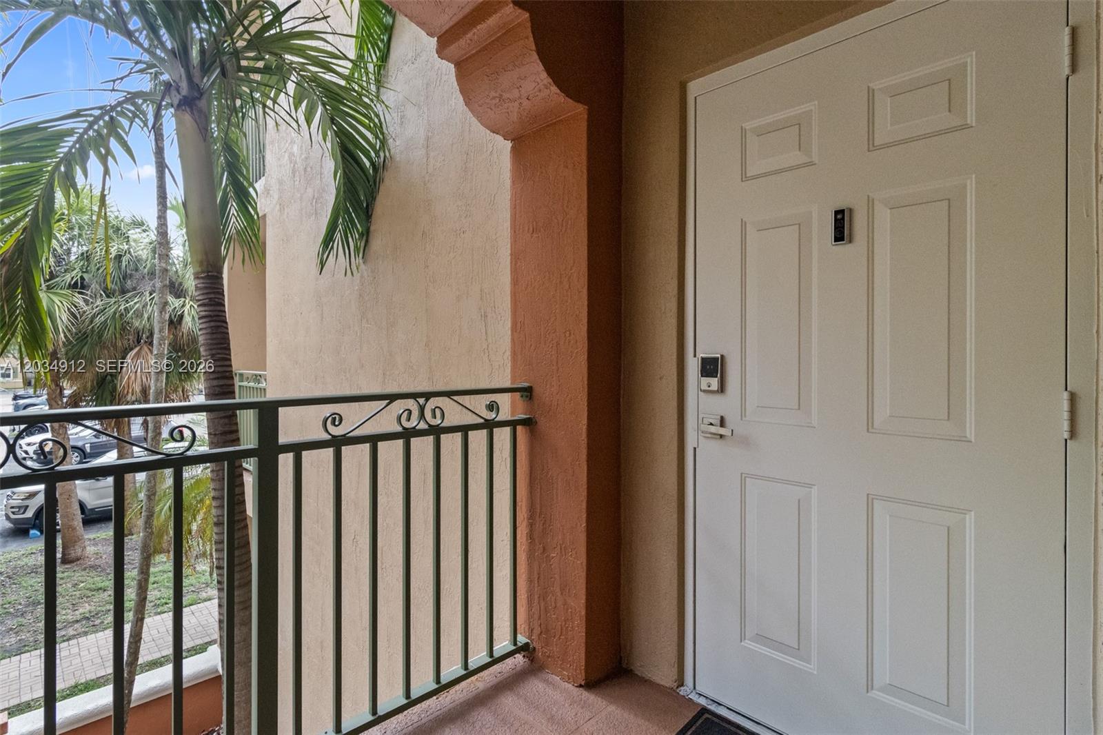 A white door with a smart lock sits on a balcony with a metal railing — 6540 NW 114th Ave # 1423, Doral FL 33178, DORAL, FL