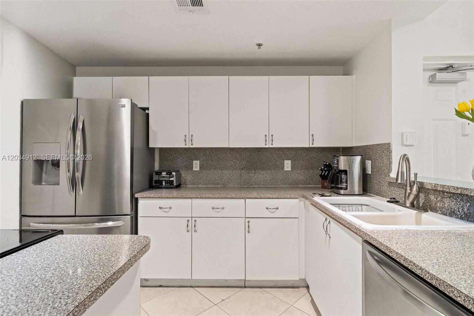 A kitchen features white cabinets, stainless steel appliances, and speckled granite countertops — 6540 NW 114th Ave # 1423, Doral FL 33178, DORAL, FL