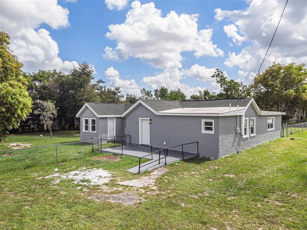 A gray, single-story house with a wheelchair ramp leading to the front entrance — 205 E CORNELL STREET, AVON PARK, FL