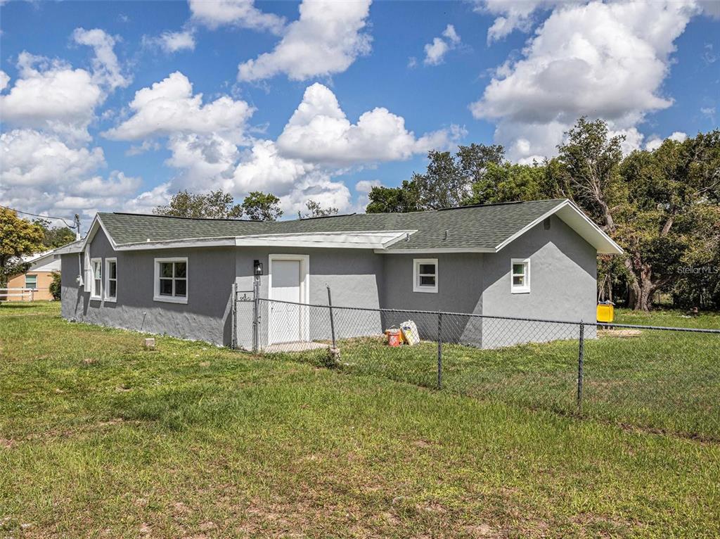 A gray, single-story house with a green shingled roof and a chain-link fenced yard — 205 E CORNELL STREET, AVON PARK, FL
