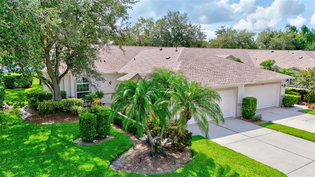 An exterior view of a single-story house with a two-car garage and palm trees — 6314 STONE RIVER ROAD, BRADENTON, FL