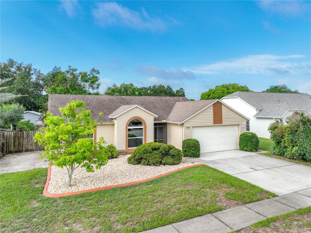 A single-story house with a beige exterior, a two-car garage, and a landscaped front yard — 859 YORKTOWNE DRIVE, ROCKLEDGE, FL