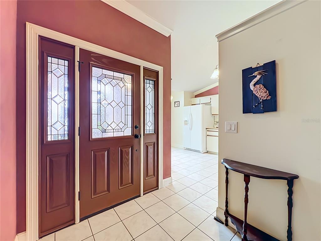 An entryway features a brown front door with glass panels, tile flooring, and a console table — 859 YORKTOWNE DRIVE, ROCKLEDGE, FL