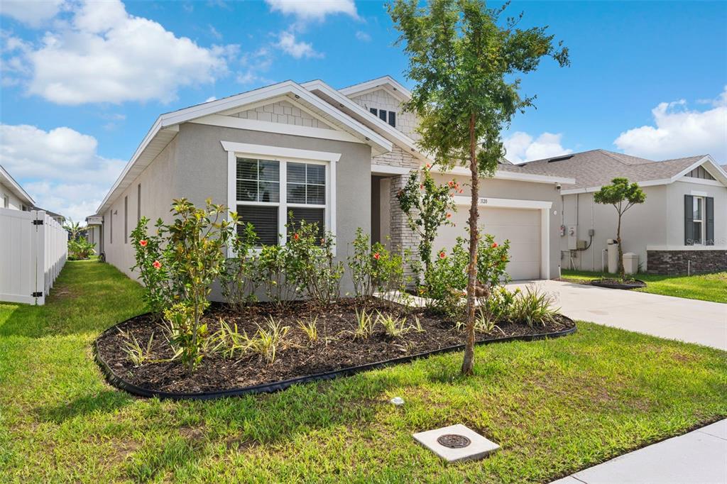 A single-story house with a gray stucco exterior, stone accents, and a two-car garage — 1120 MATTIE POINTE BOULEVARD, AUBURNDALE, FL