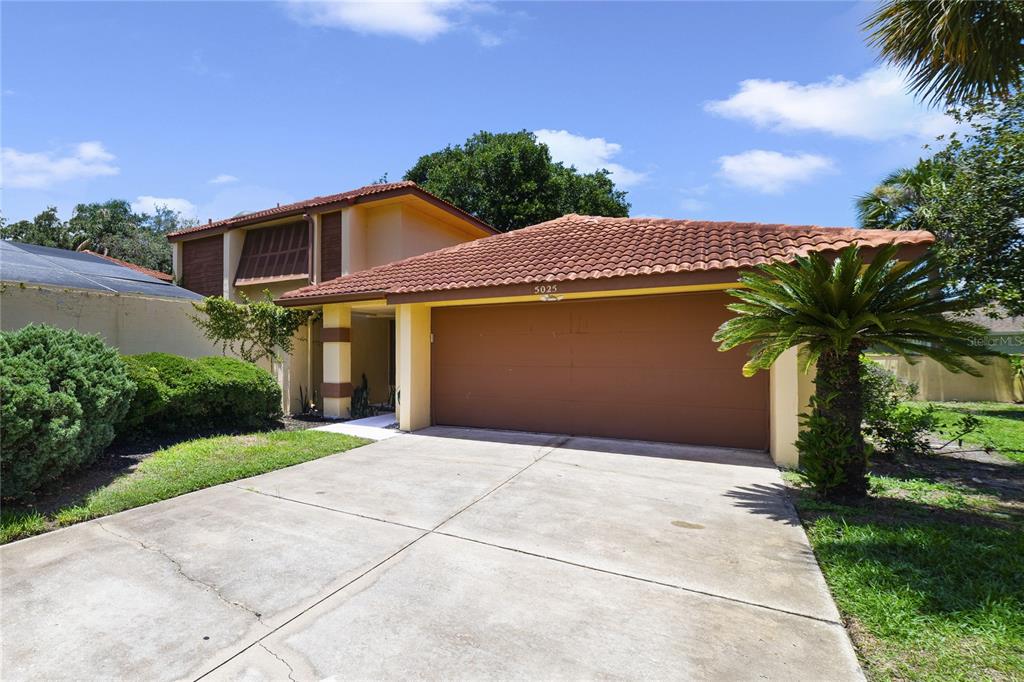 A two-story house with a brown tile roof, a two-car garage, and a concrete driveway — 5025 BERMUDA CIRCLE UNIT 5025, ORLANDO, FL