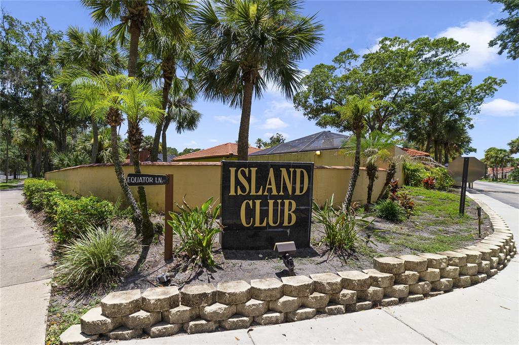 A stone retaining wall sits in front of an Island Club sign and palm trees — 5025 BERMUDA CIRCLE UNIT 5025, ORLANDO, FL