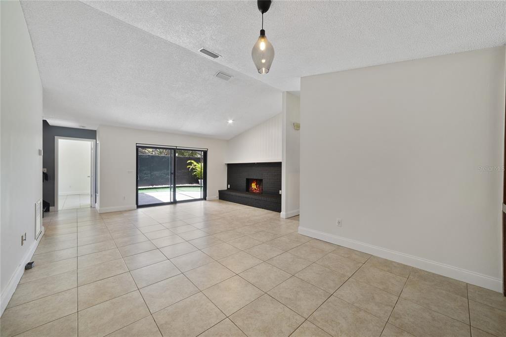A living room features light tile floors, a black brick fireplace, and sliding glass doors — 5025 BERMUDA CIRCLE UNIT 5025, ORLANDO, FL