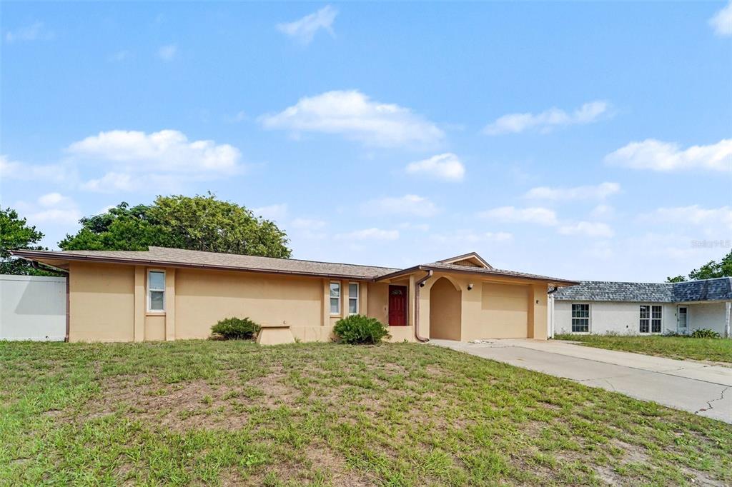 A tan, single-story house with a red front door and an attached garage — 7612 DALE DRIVE, PORT RICHEY, FL