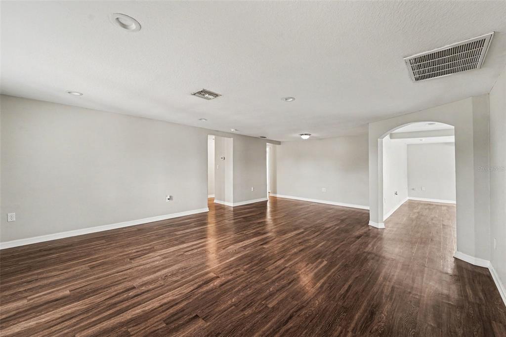 An empty room with light gray walls, dark wood-look flooring, and recessed ceiling lighting — 7612 DALE DRIVE, PORT RICHEY, FL