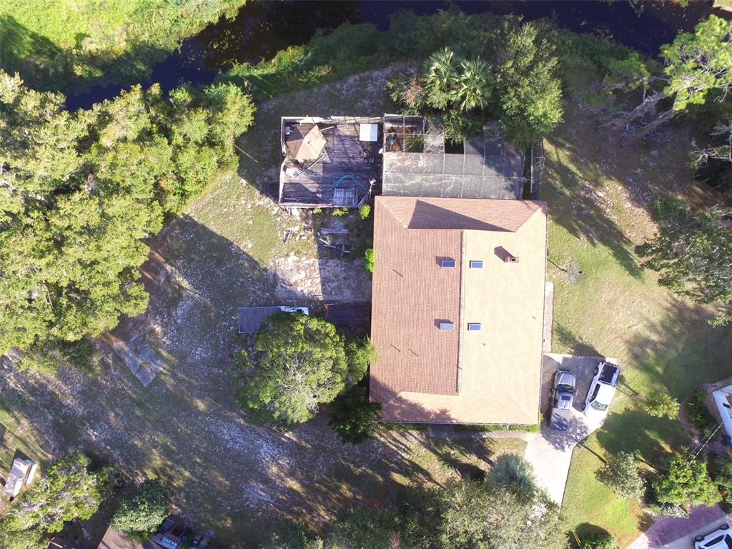 An aerial view shows a house with a brown roof, a deck, and a screened enclosure — 35412 CRESCENT DRIVE, FRUITLAND PARK, FL