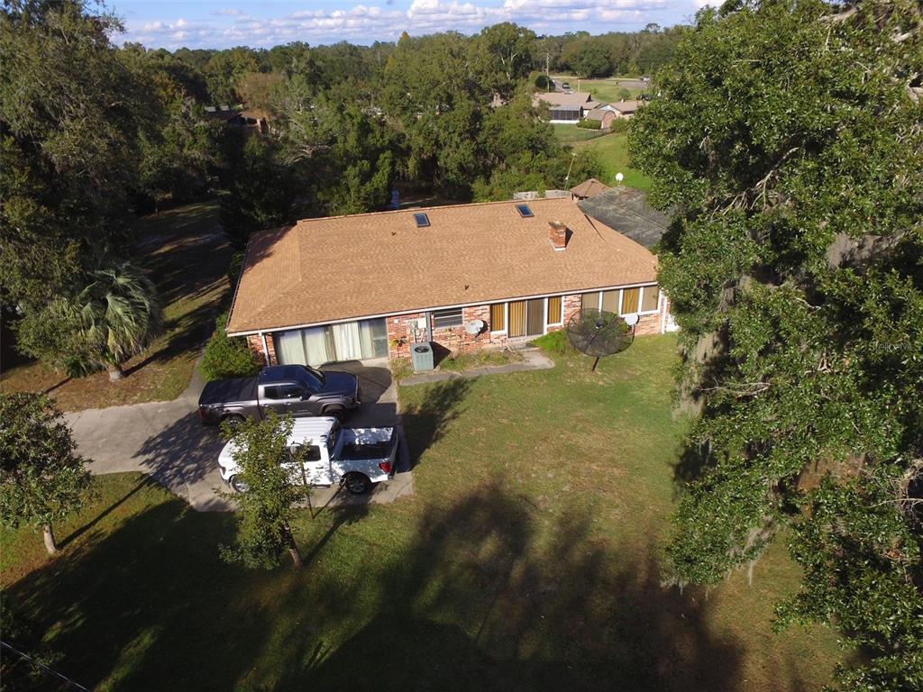An aerial view shows a single-story brick house with a brown shingled roof and driveway — 35412 CRESCENT DRIVE, FRUITLAND PARK, FL
