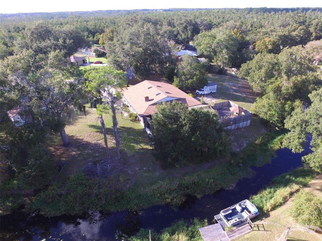 An aerial view shows a house with a brown roof, a fenced yard, and a canal — 35412 CRESCENT DRIVE, FRUITLAND PARK, FL