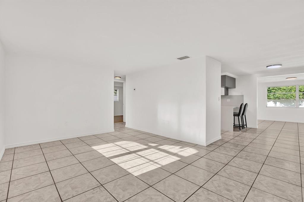 An open-concept living area with white walls and light-colored tile flooring — 6701 PARKSIDE DRIVE, NEW PORT RICHEY, FL