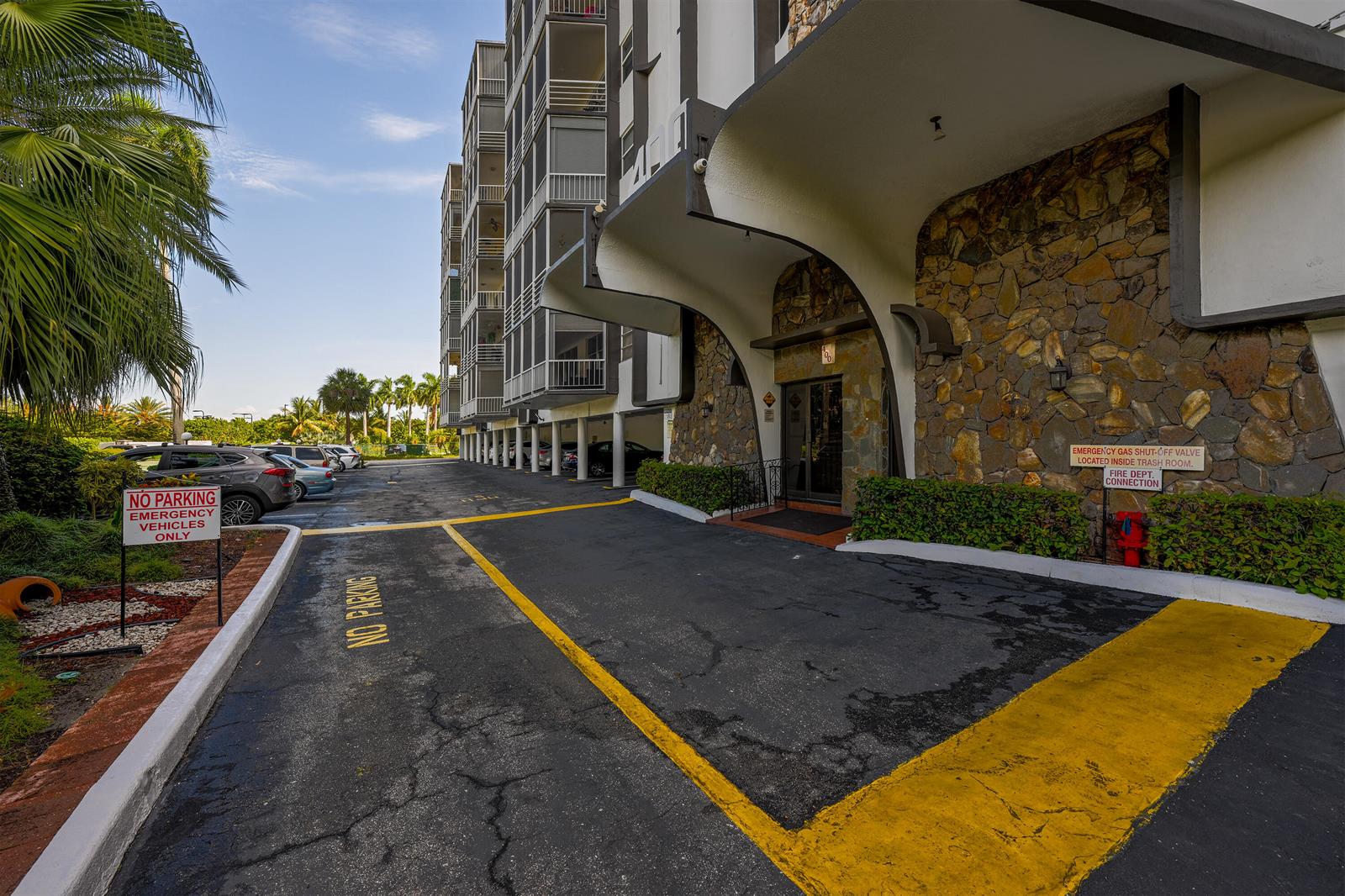 The exterior of a multi-story apartment building features a stone-accented entrance and covered driveway — 400 Diplomat Parkway # 612, Hallandale Beach FL 33009, HALLANDALE BEACH, FL