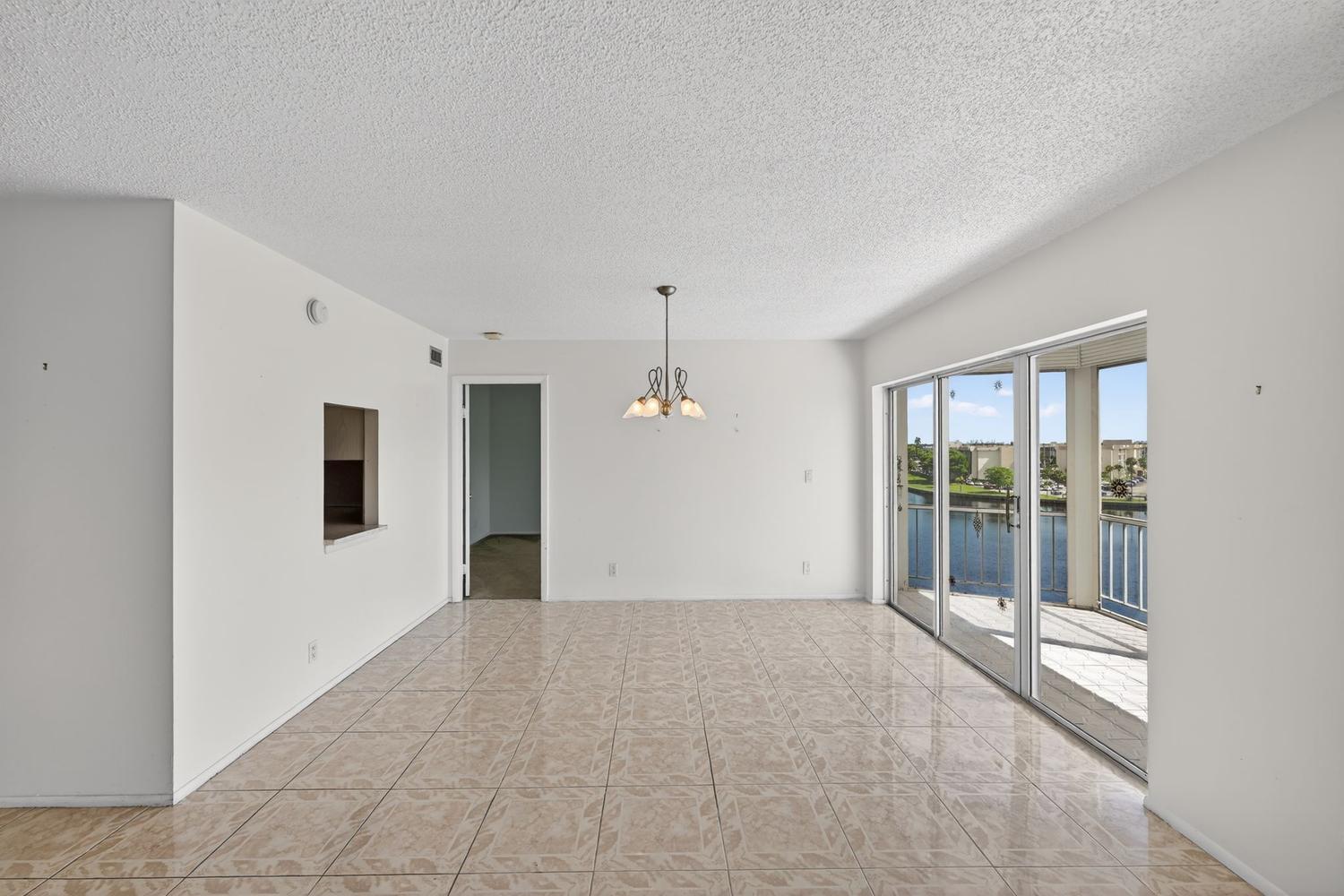 An empty dining room with tiled floors, a chandelier, and sliding glass doors to a balcony — 400 Diplomat Parkway # 612, Hallandale Beach FL 33009, HALLANDALE BEACH, FL