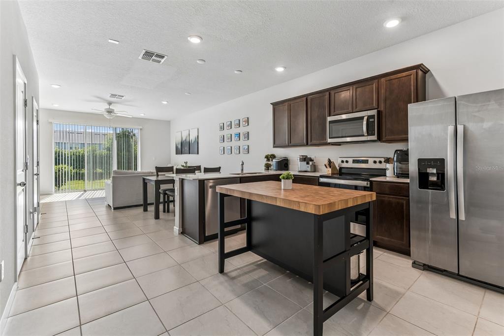 A kitchen with dark wood cabinets, stainless steel appliances, and a wooden kitchen island — 31357 AMBERVIEW BEND, WESLEY CHAPEL, FL