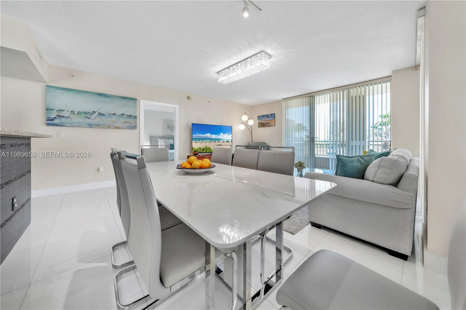 A dining area with a marble table and chairs sits adjacent to a living room — 2080 S Ocean Dr # 202, Hallandale Beach FL 33009, HALLANDALE BEACH, FL