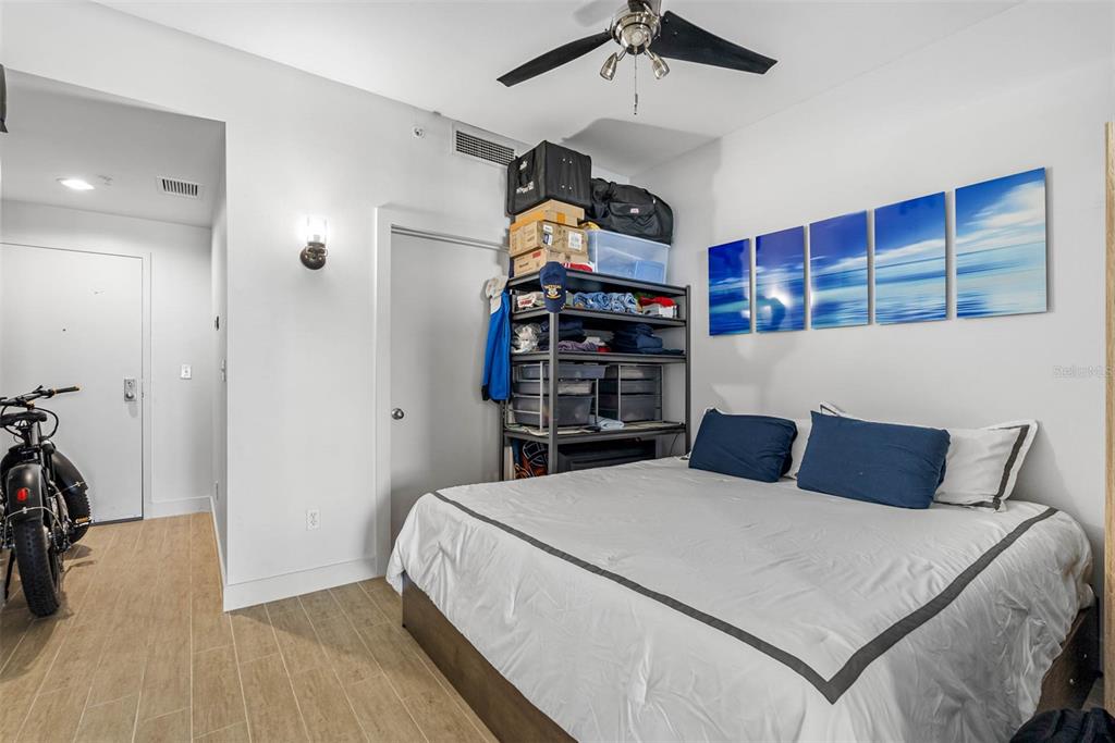 A bedroom features a bed, a metal storage rack, and a bicycle on wood-look flooring — 1120 E KENNEDY BOULEVARD UNIT 1417, TAMPA, FL