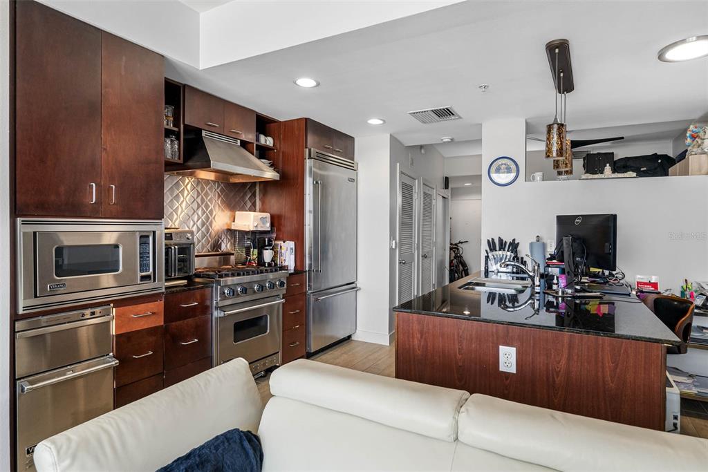 A kitchen features dark wood cabinetry, stainless steel appliances, and a black granite island countertop — 1120 E KENNEDY BOULEVARD UNIT 1417, TAMPA, FL