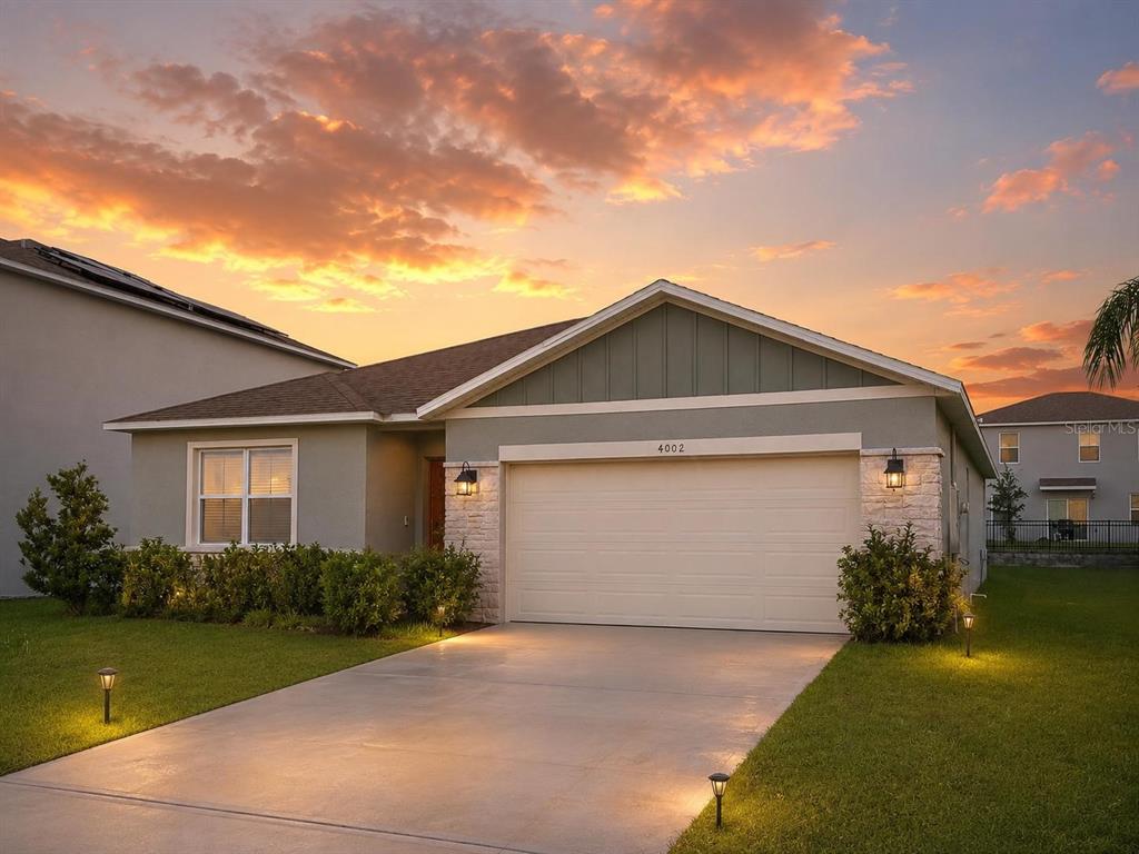A single-story suburban house with a two-car garage, stone accents, and a concrete driveway — 4002 MALAWI TRAIL, ST CLOUD, FL