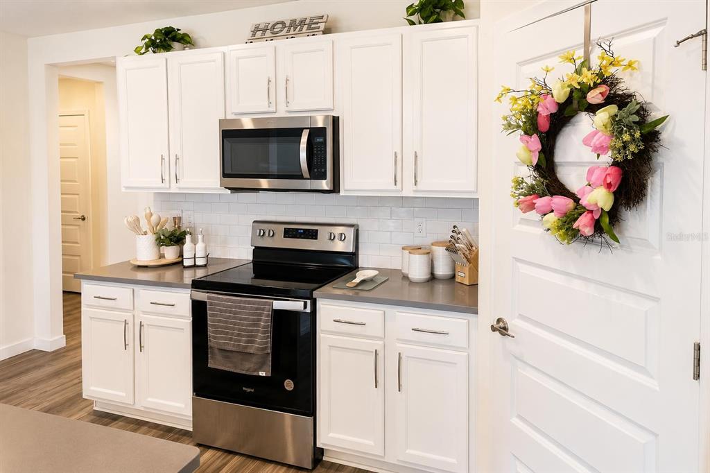 A kitchen features white cabinets, stainless steel appliances, gray countertops, and a subway tile backsplash — 4002 MALAWI TRAIL, ST CLOUD, FL
