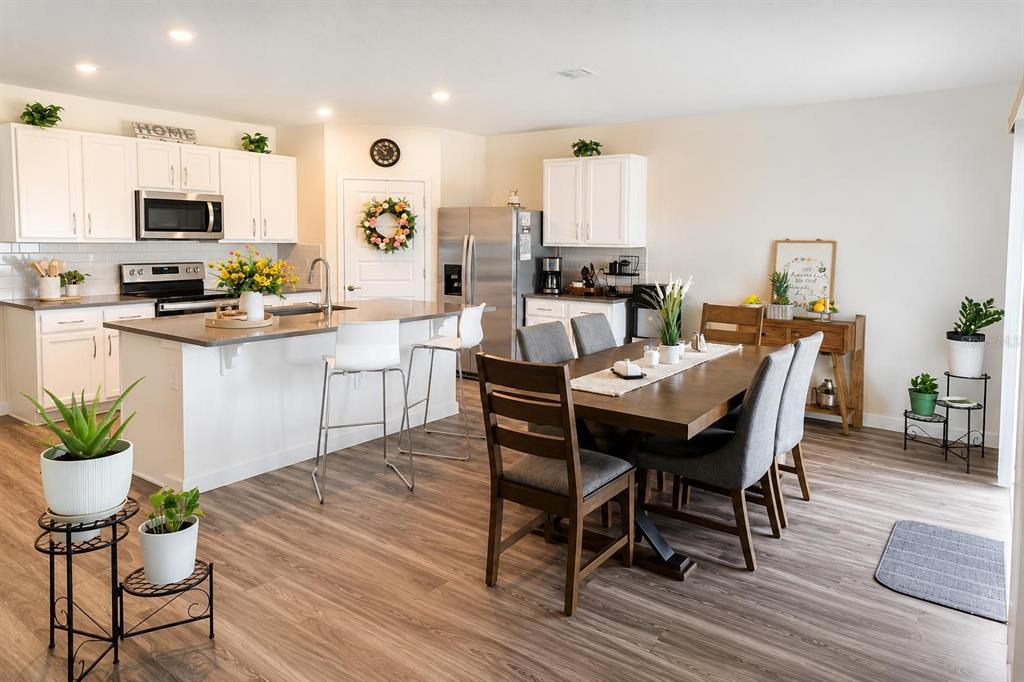A kitchen with white cabinets and a center island opens into a dining area — 4002 MALAWI TRAIL, ST CLOUD, FL